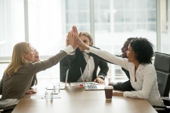 building relationships during the sales journey, a group of people high fiving over a conference table